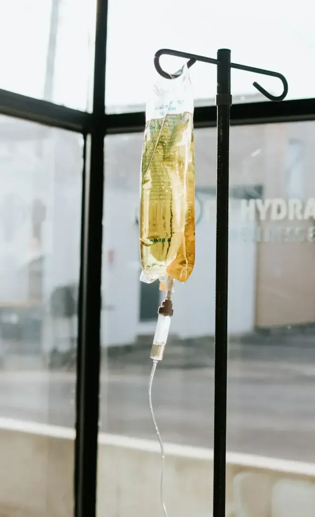 Hangover iv - drip filled with a golden solution, hanging from an IV stand in a wellness center, used for rapid hydration and hangover recovery.