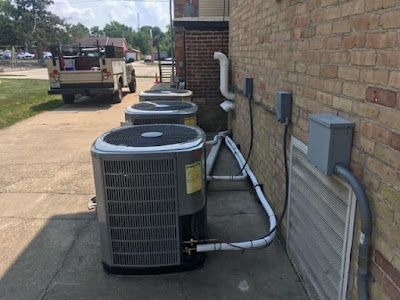 A row of air conditioners are sitting outside of a brick building.