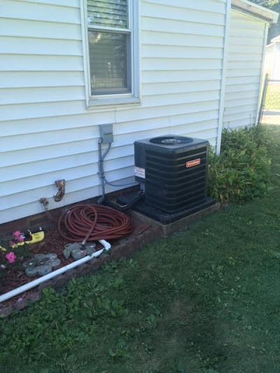An air conditioner is sitting on the side of a house next to a window.