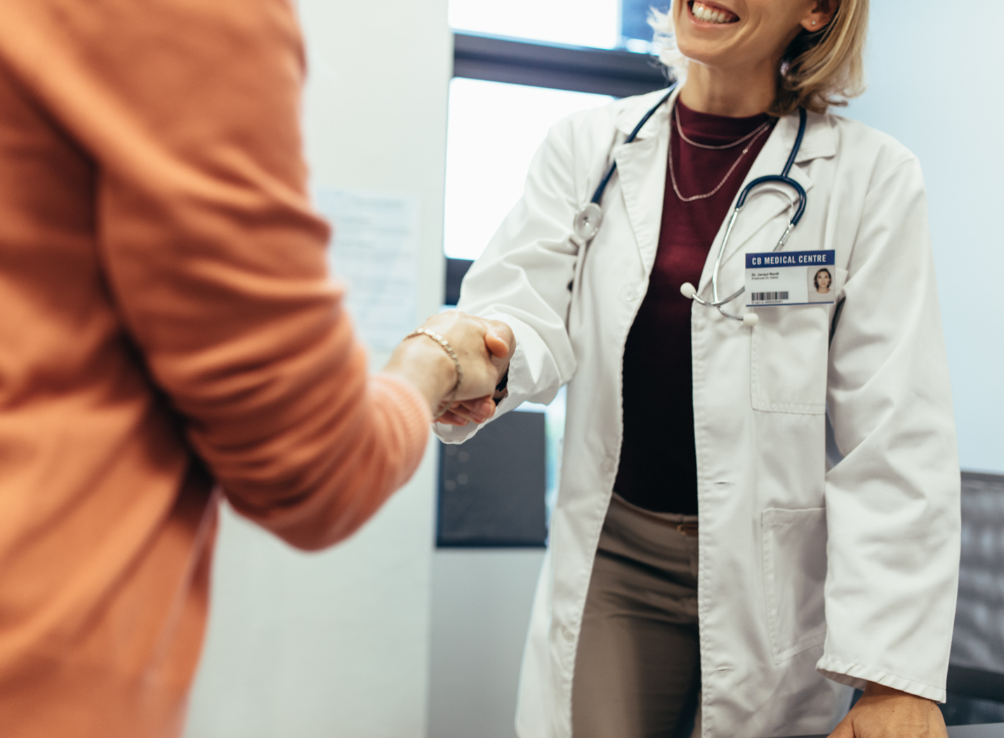 Doctor shaking hands with a patient in a bright clinic office