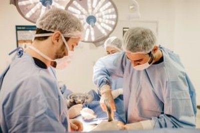 Two surgeons in blue scrubs operate in a brightly lit operating room Two surgeons in blue scrubs operate in a brightly lit operating room