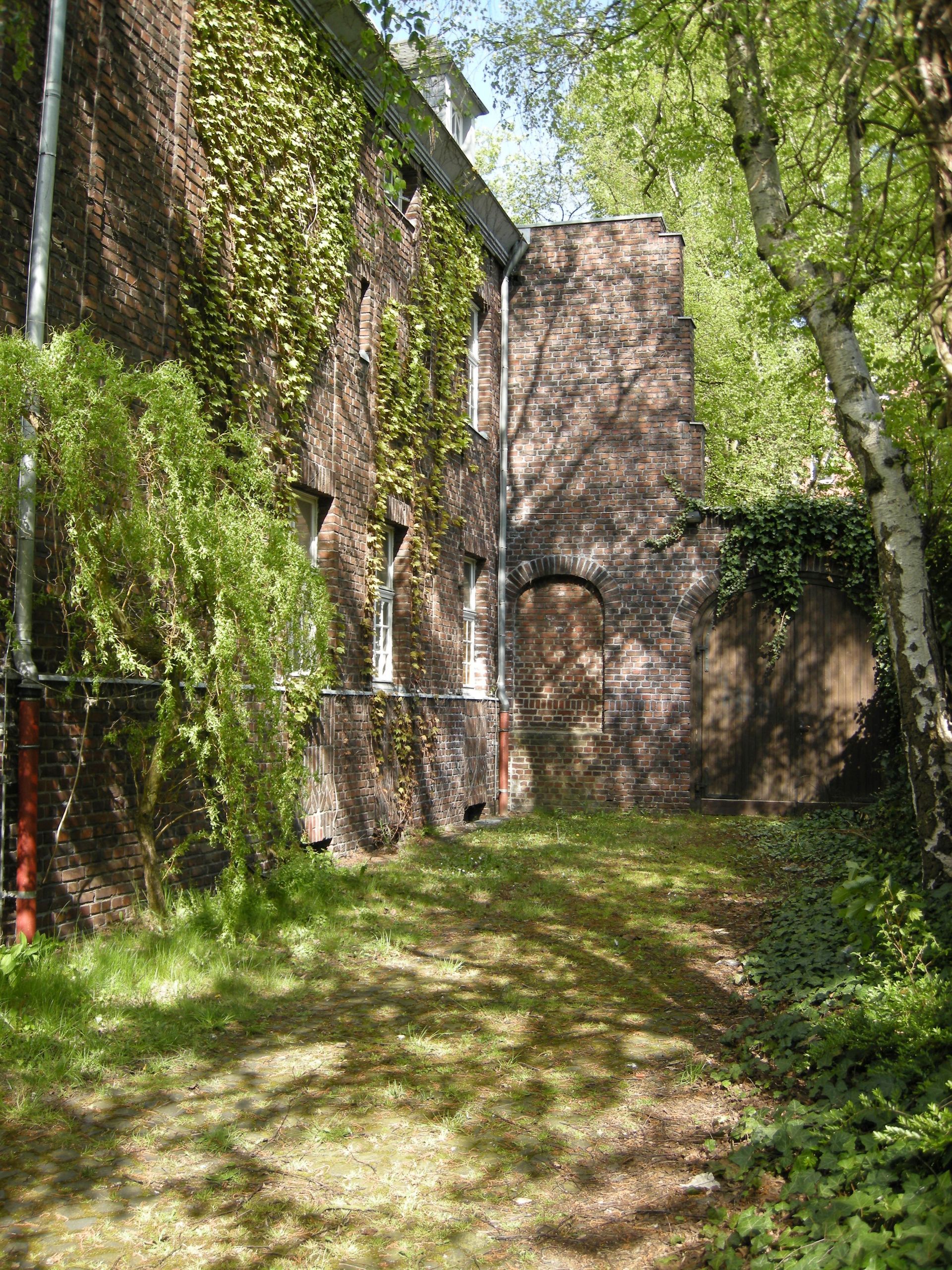 A brick building is surrounded by trees and grass in the middle of a forest.
