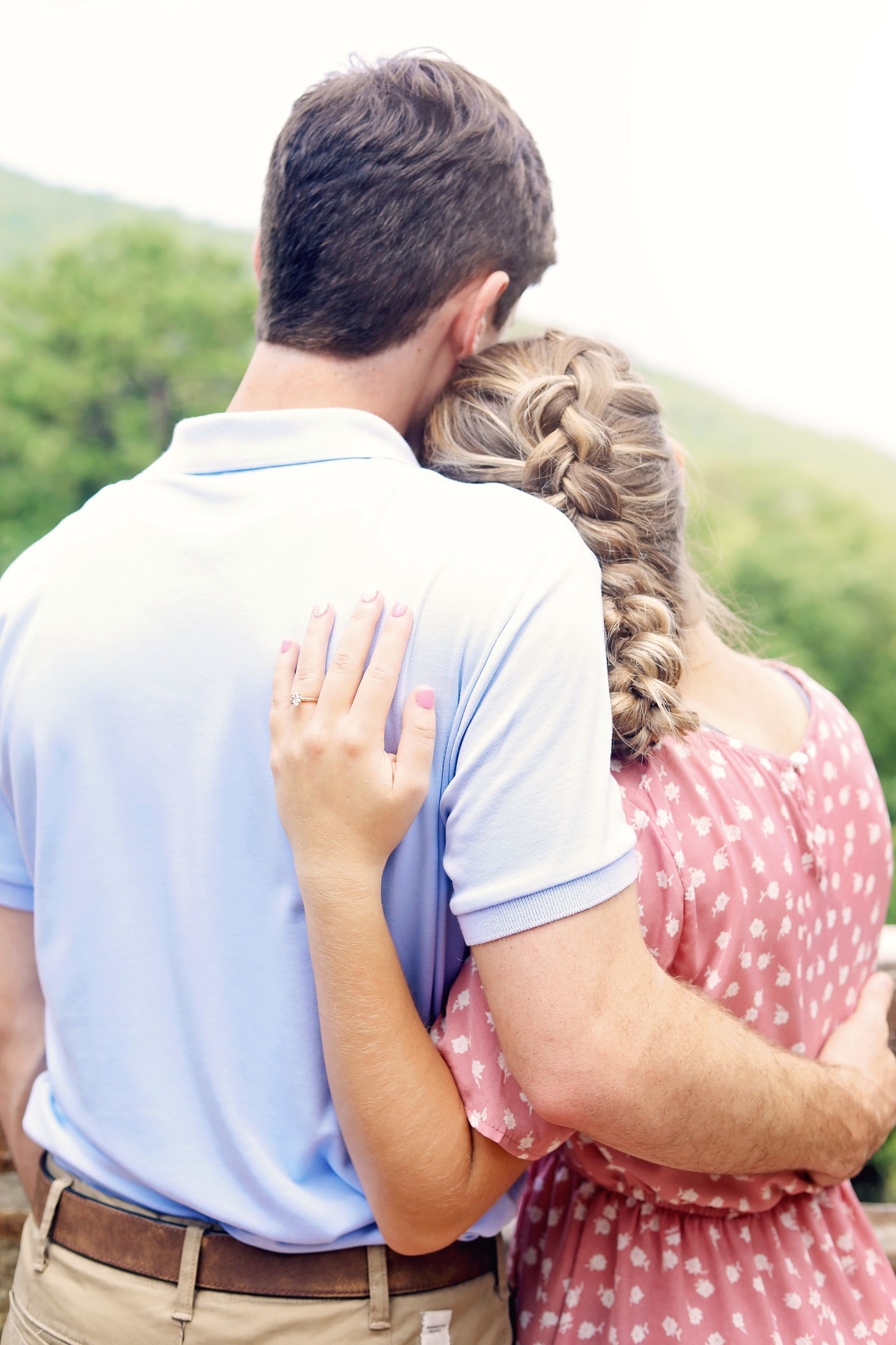 Couple embracing outdoors, seen from behind, with a hand on the man's back.