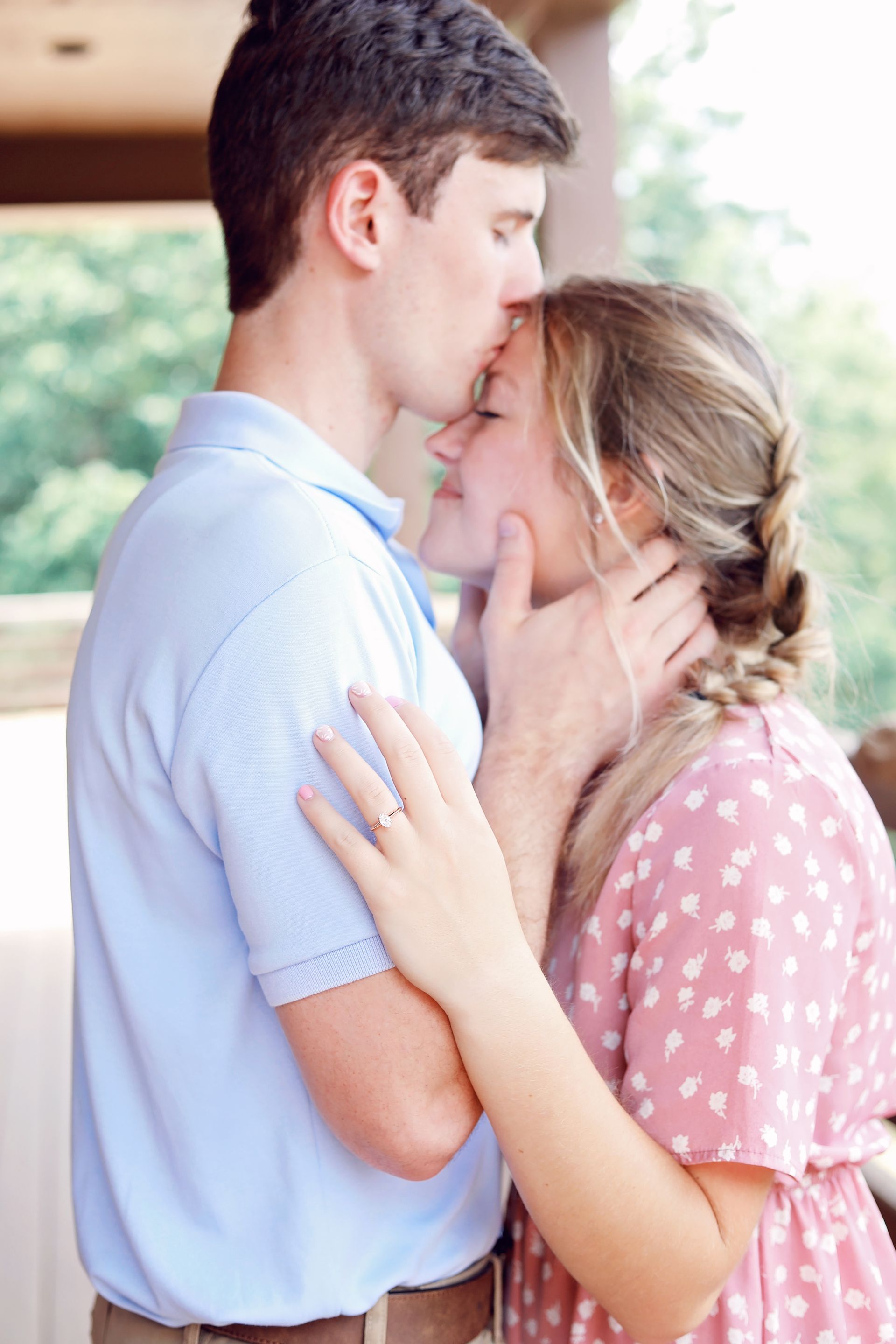 Couple embracing closely indoors, with the woman in a pink polka-dot dress and the man in a blue shirt