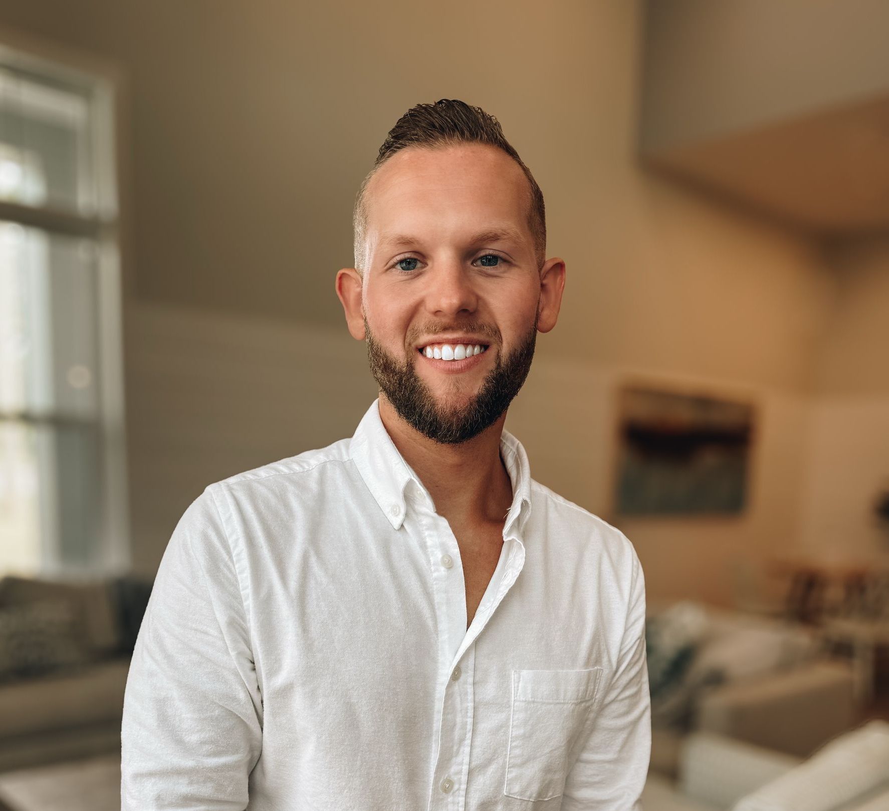 Smiling man in a white shirt standing in a bright living room