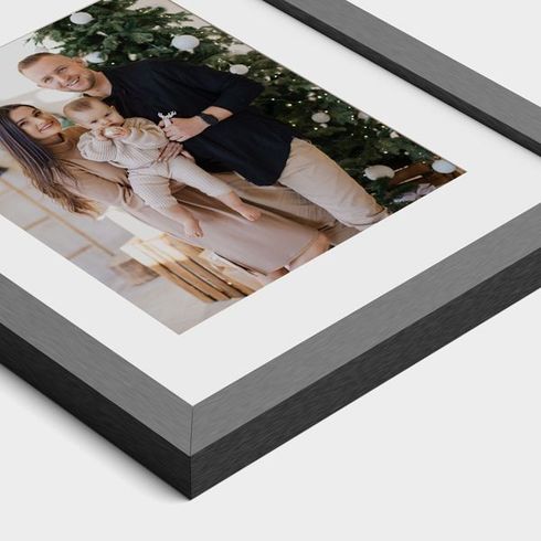 Framed family portrait with a couple holding a baby, shown on a white mat and dark frame