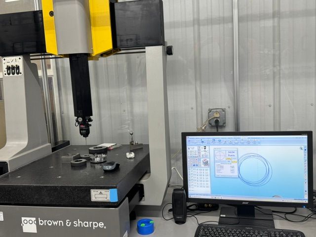Brown & Sharpe coordinate measuring machine with computer monitor displaying measurement software in a lab.