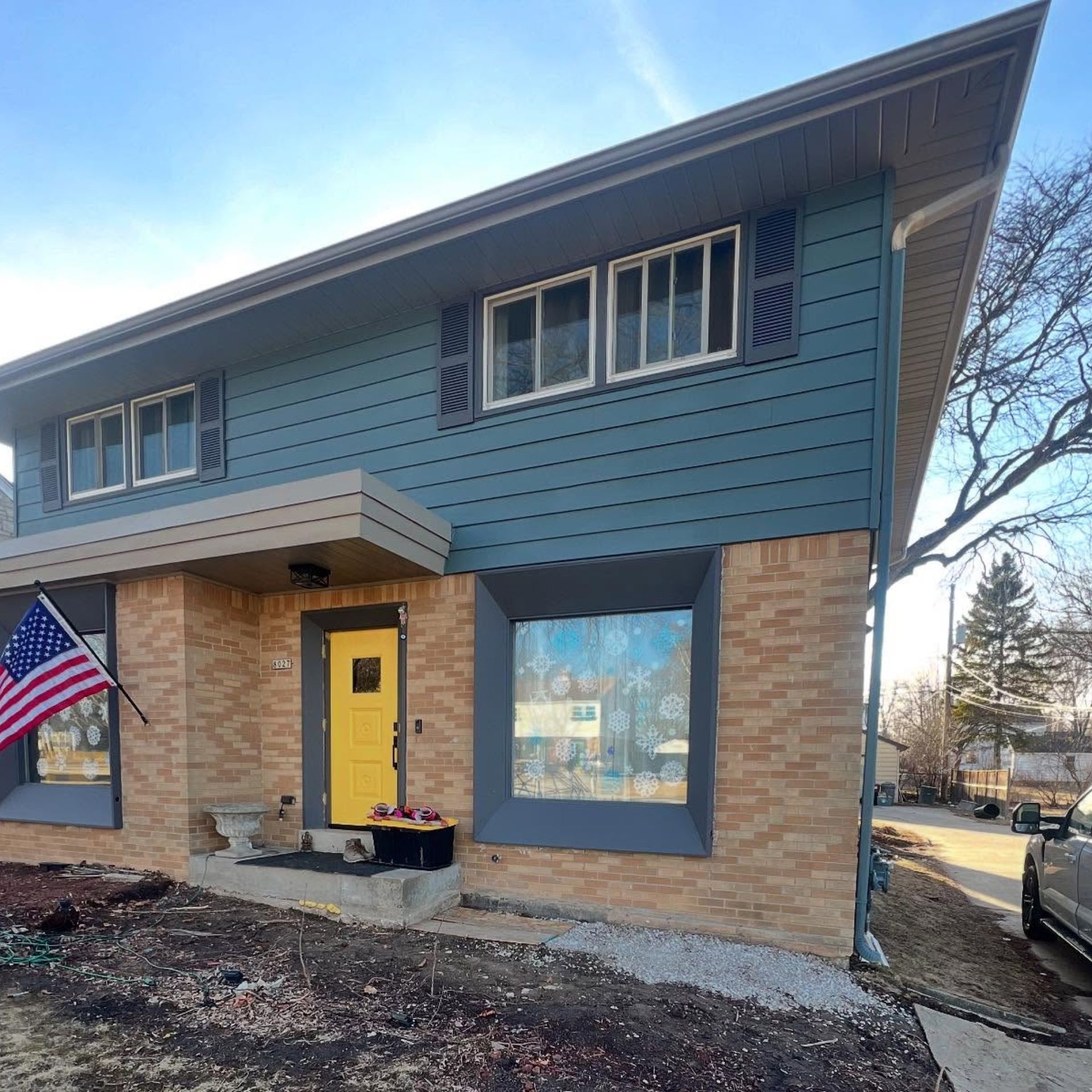 WCL ConstructionPaint Carpentry Inc -  A house with a yellow door and an american flag in front of it