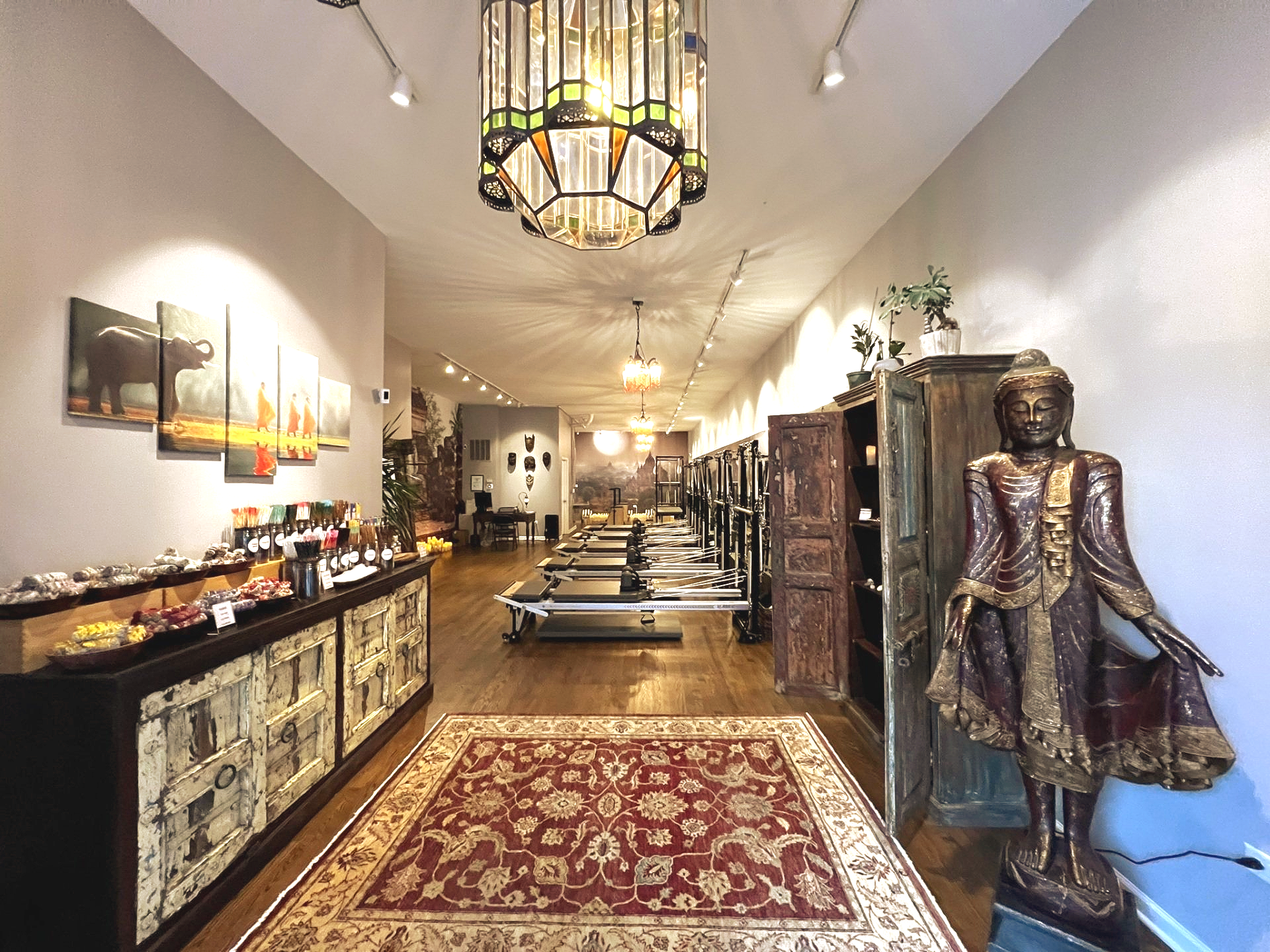 Image of Metaphysical Pilates studio with reformers, sale counter and female buddha statue