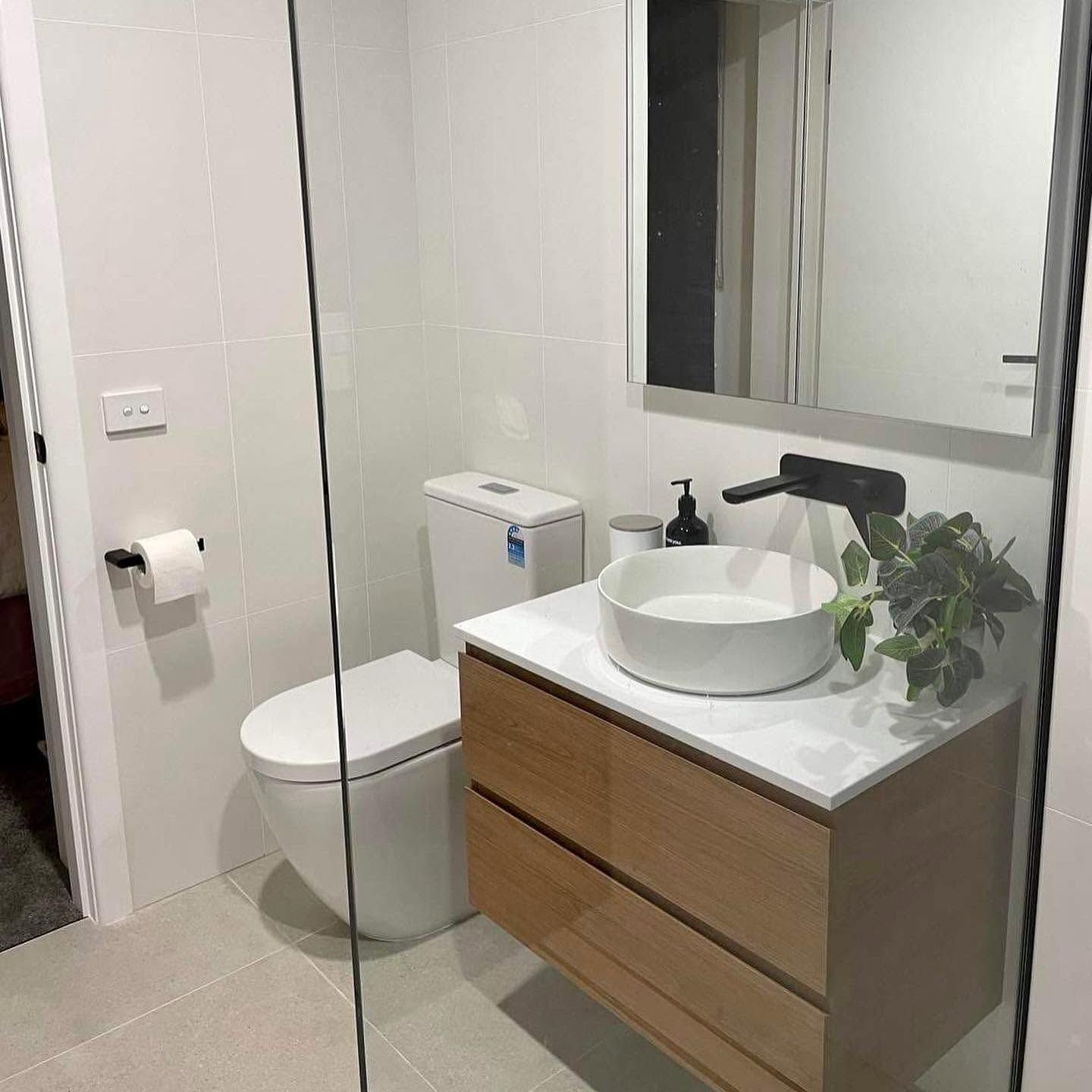 Modern bathroom with toilet, vanity sink, mirror, and shower glass partition