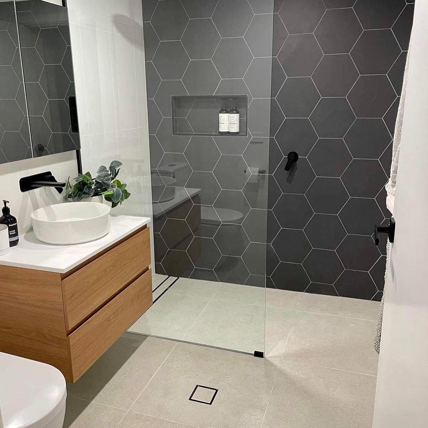 Modern bathroom with gray hex tile shower, white vanity, and light tile floor