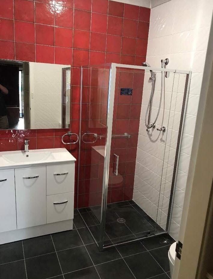 Modern bathroom with red tile, white vanity, and a glass shower enclosure. Modern bathroom with red tile, white vanity, and a glass shower enclosure.
