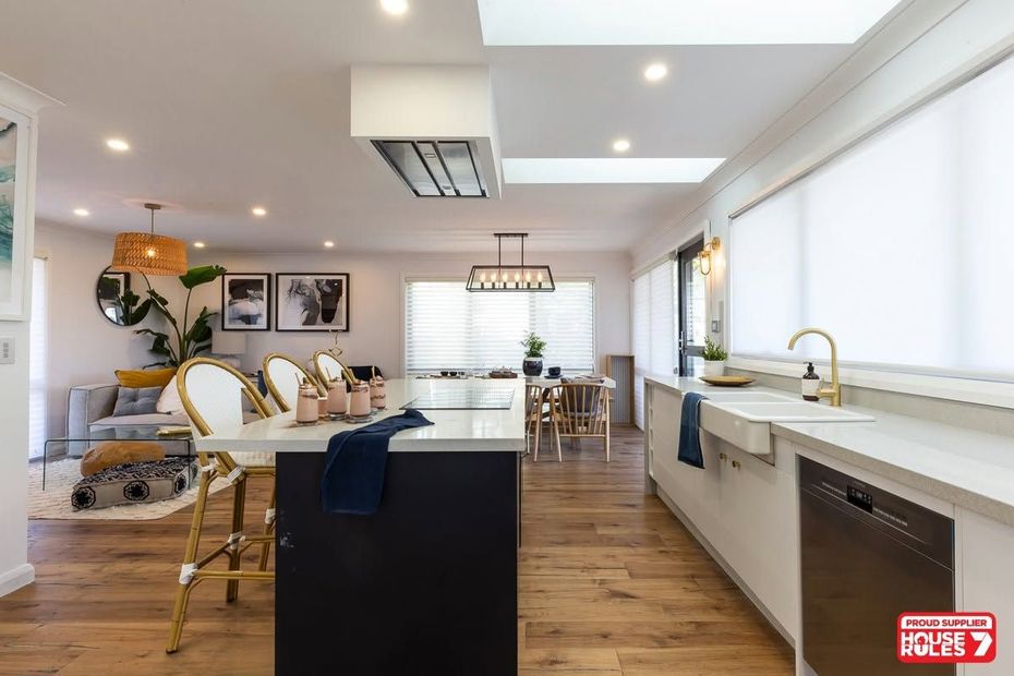 Modern open-plan kitchen and dining area with white cabinetry, wood floors, and pendant lighting Modern open-plan kitchen and dining area with white cabinetry, wood floors, and pendant lighting