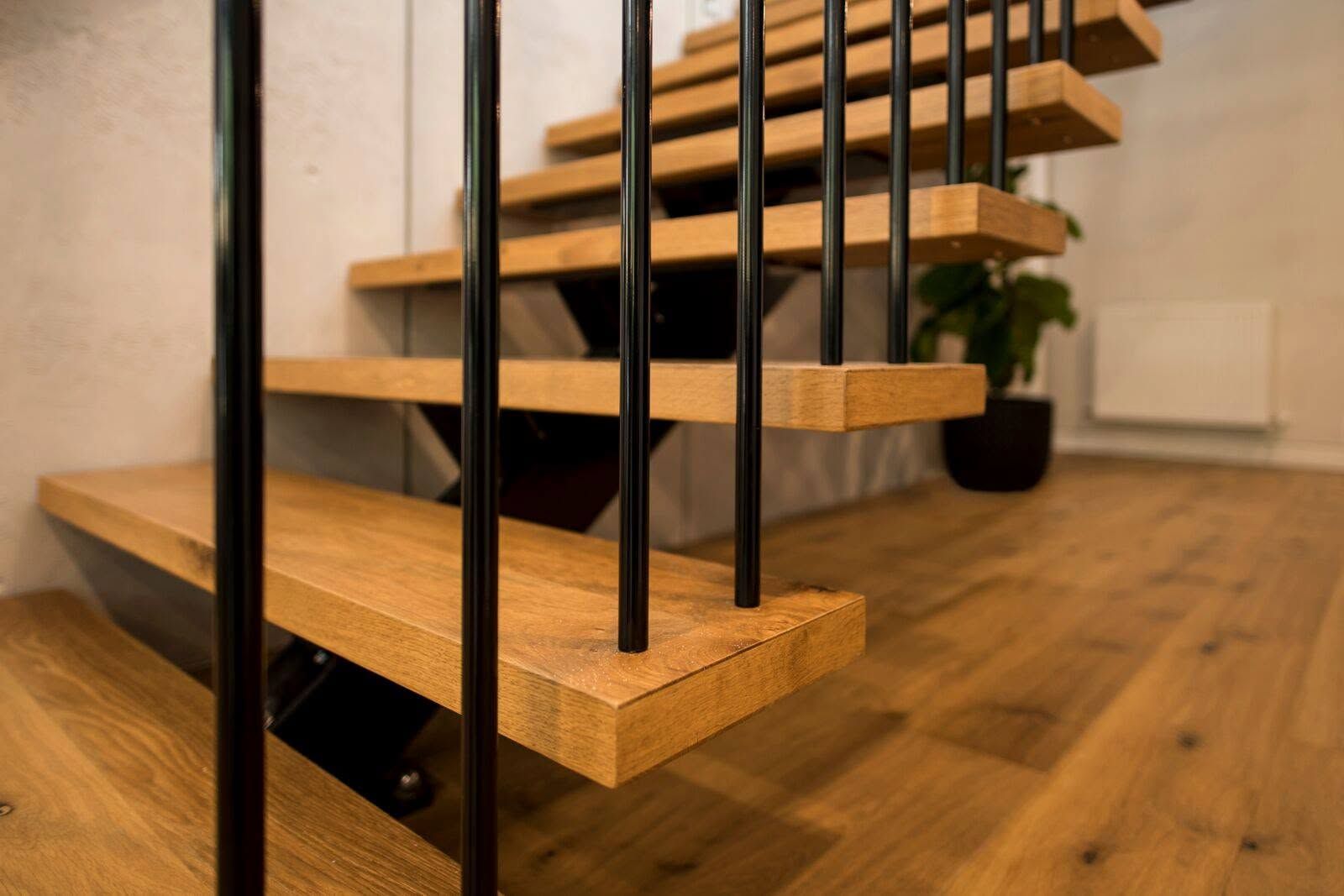 Wooden staircase with black metal rails in a modern interior, viewed from below