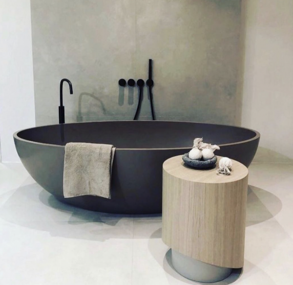 Modern bathroom with a matte black freestanding tub, towel, and wood vanity stool