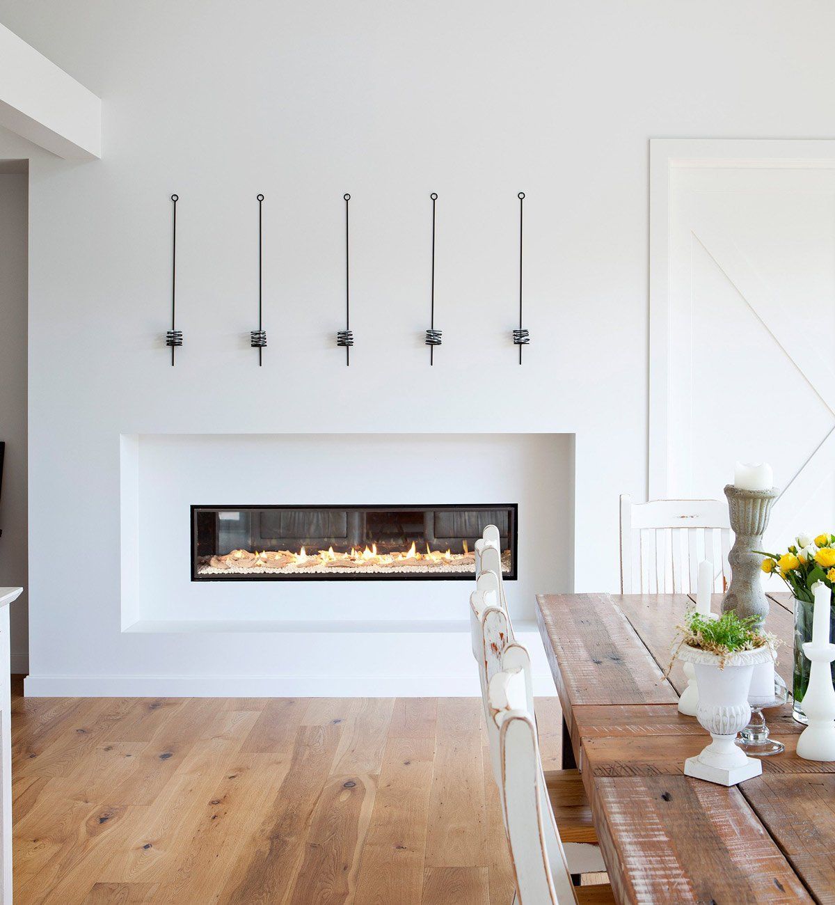 Minimalist dining room with a modern linear fireplace and rustic wooden table
