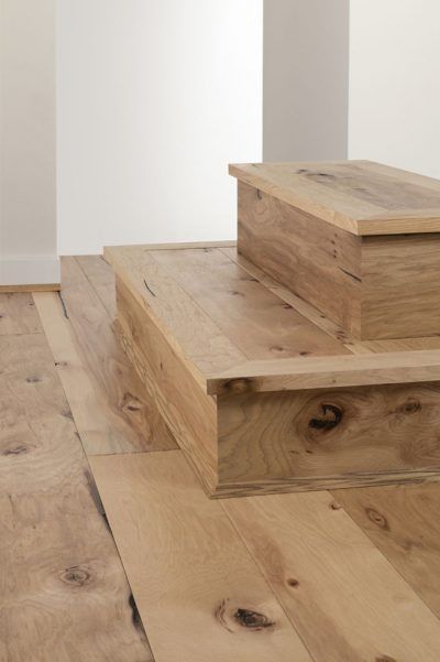 Wooden steps on a light hardwood floor beside a white wall