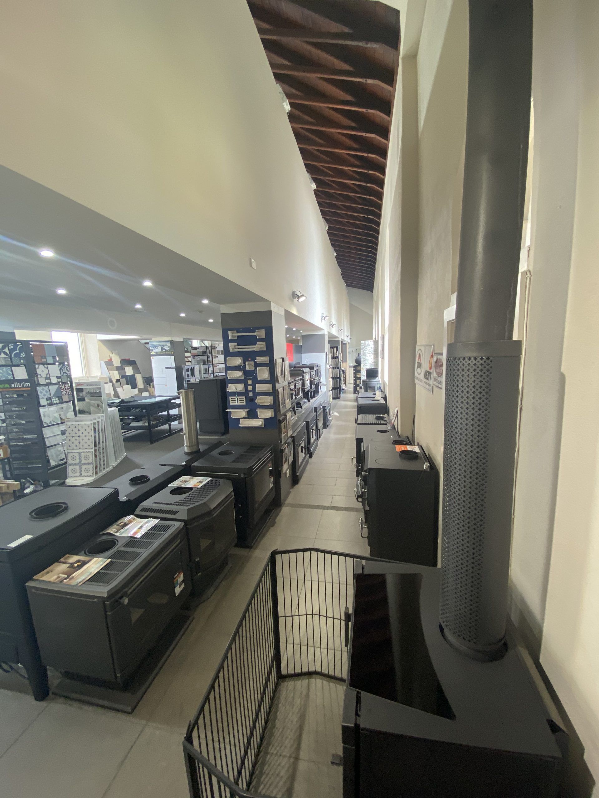 Long retail aisle with clothing displays, shelves, and tall columns under bright store lighting
