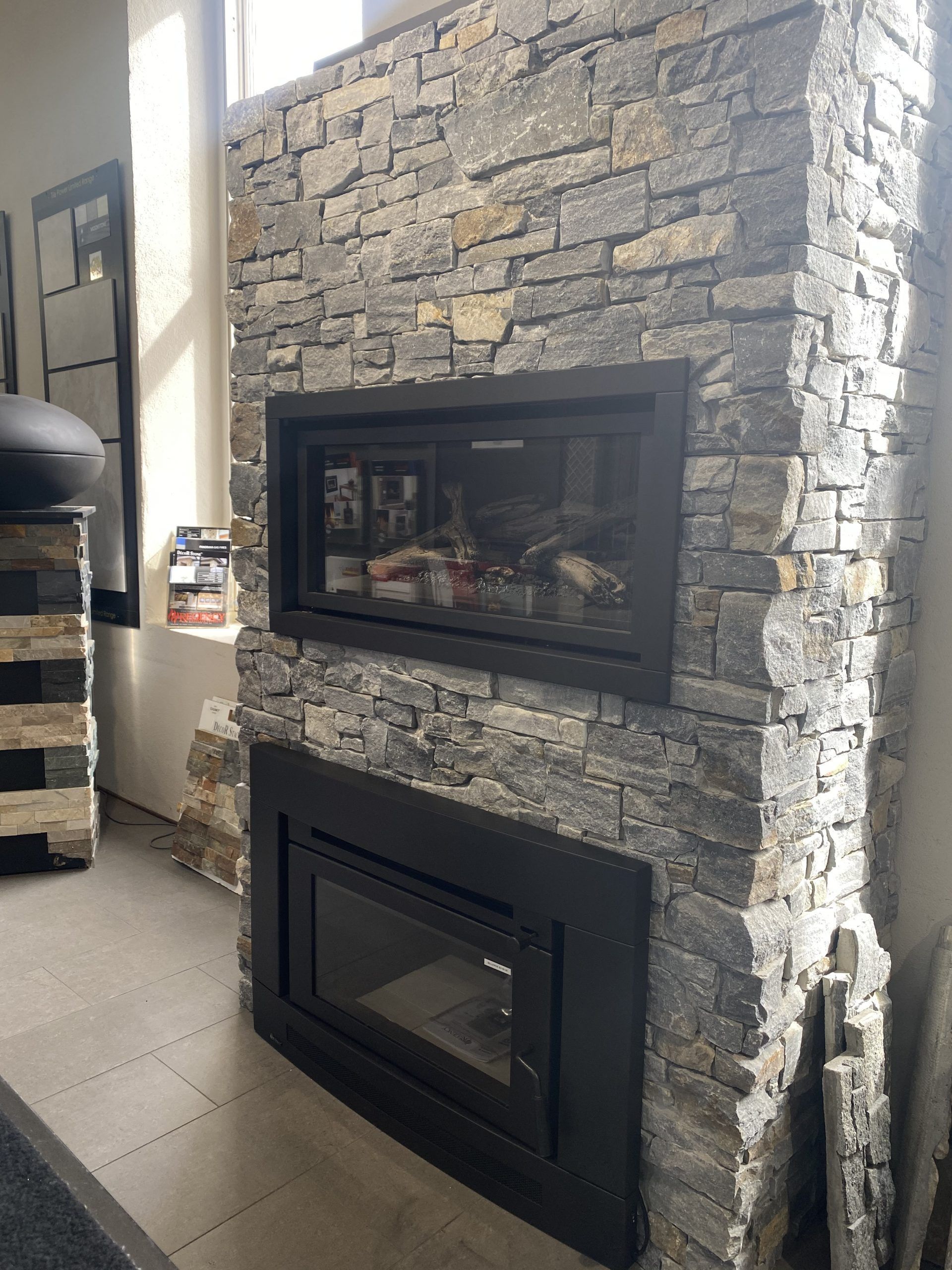 Stone fireplace with a black glass-front insert in a modern tiled room