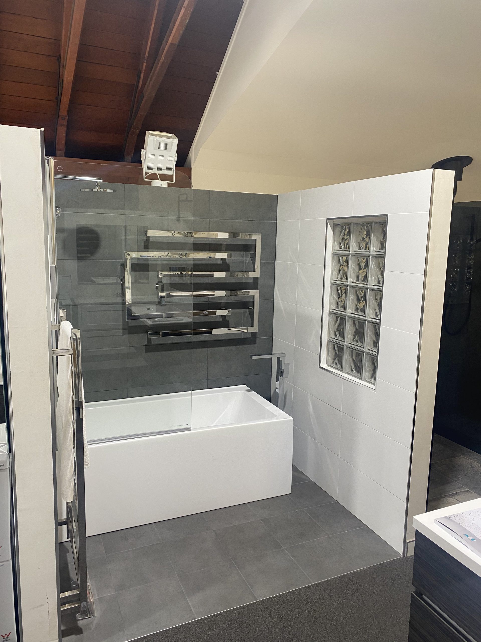 Interior of a small room with gray walls, white cabinets, and a built-in sink under a sloped ceiling