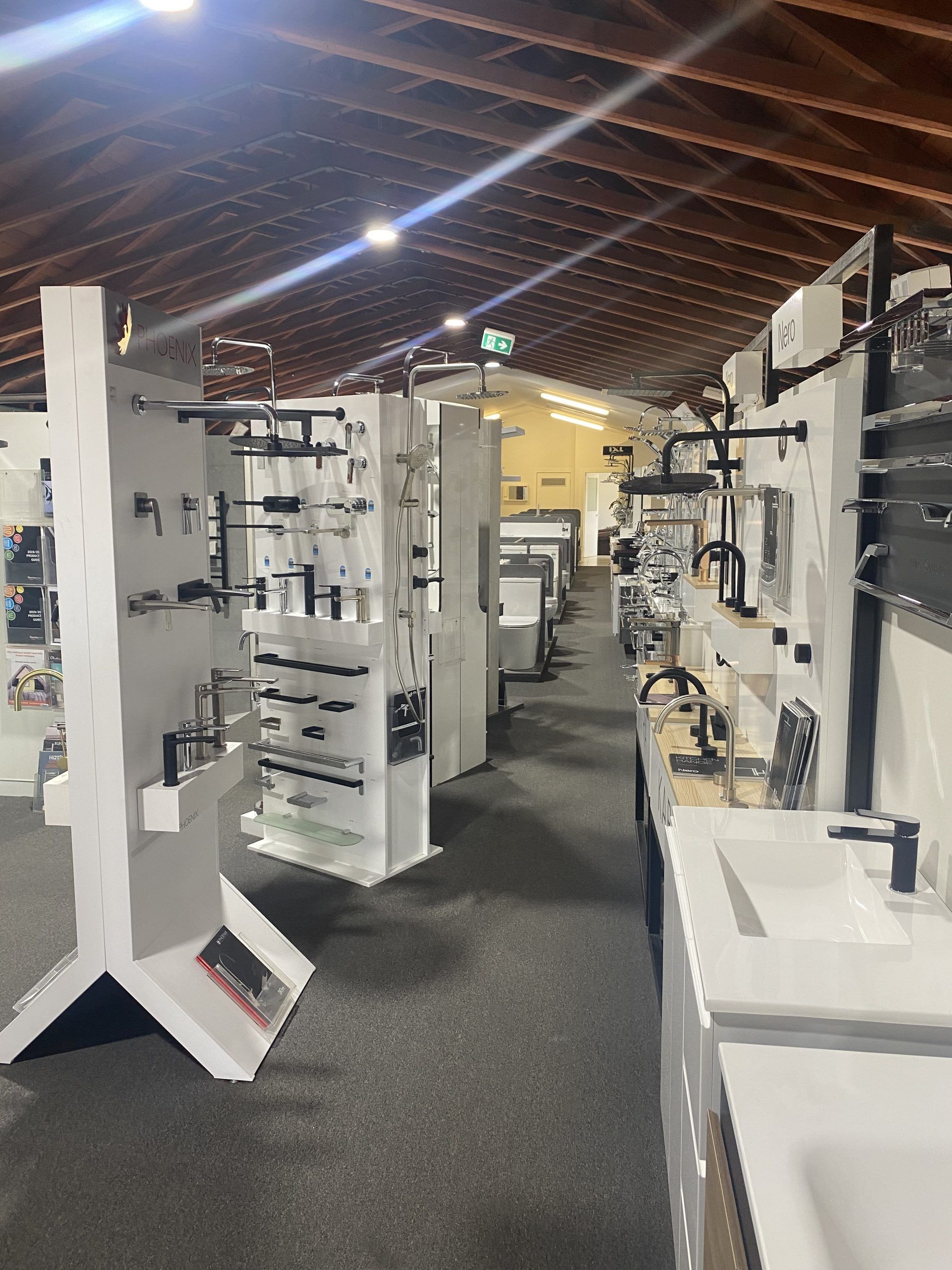 Indoor trade show aisle with white display panels and equipment under a high, tented ceiling.