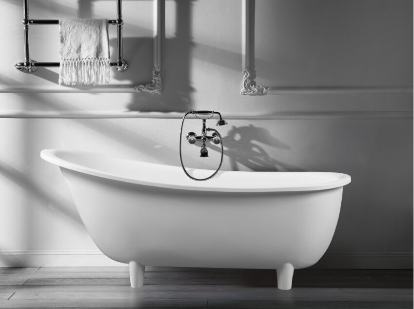 Black-and-white bathroom with a freestanding tub and wall-mounted faucet beneath a shelf.