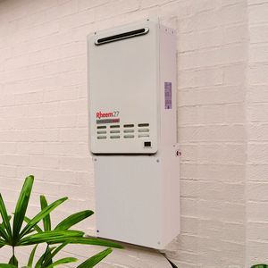 Wall-mounted white Rheem unit on a white brick wall, with a green plant in the foreground. Wall-mounted white Rheem unit on a white brick wall, with a green plant in the foreground.