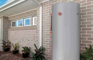 Outdoor water heater beside a brick house wall and potted plants on a patio Outdoor water heater beside a brick house wall and potted plants on a patio
