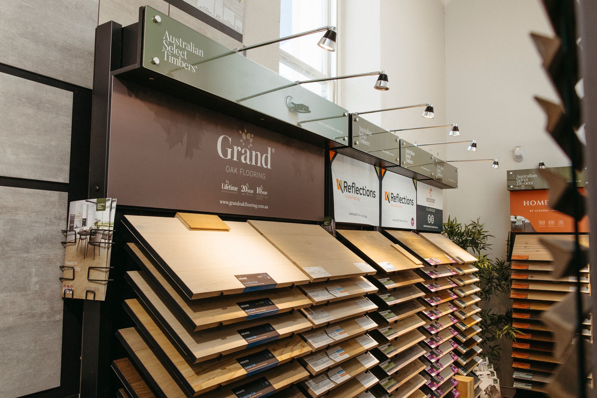 A flooring showroom aisle with rows of carpet and tile samples under bright ceiling lights.
