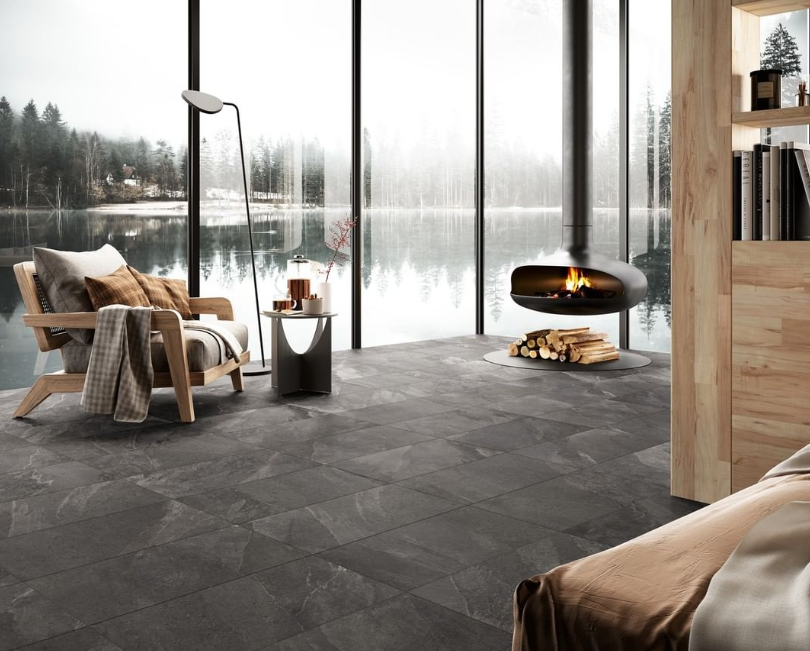 Modern lakeside living room with floor-to-ceiling windows, fireplace, armchair, and dark stone floor Modern lakeside living room with floor-to-ceiling windows, fireplace, armchair, and dark stone floor