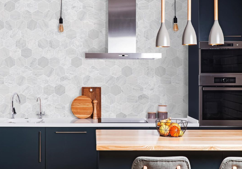 Modern kitchen with dark cabinets, light hex tile backsplash, stainless hood, and pendant lights over an island Modern kitchen with dark cabinets, light hex tile backsplash, stainless hood, and pendant lights over an island