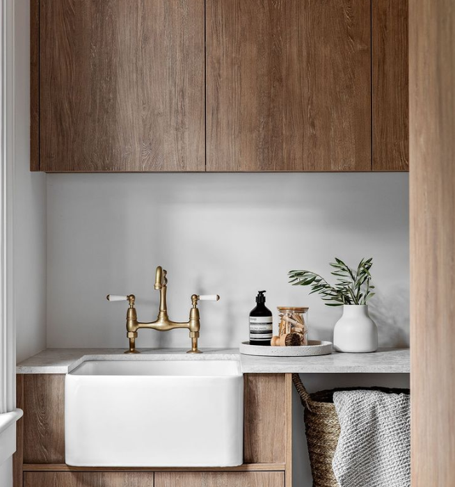 Modern bathroom vanity with brass faucet, white sink, wood cabinets, and decor accents