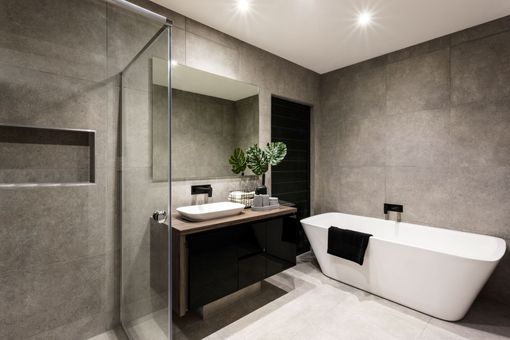 Modern bathroom with a freestanding tub, vanity, and glass shower, finished in gray stone tiles.