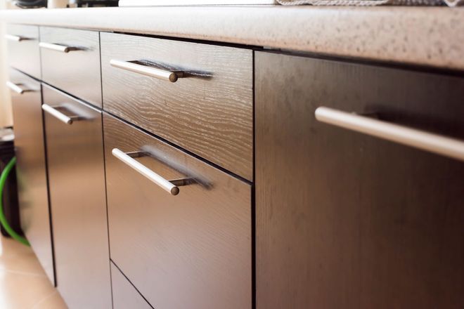 Modern kitchen cabinets with silver handles and a dark wood finish, viewed close up