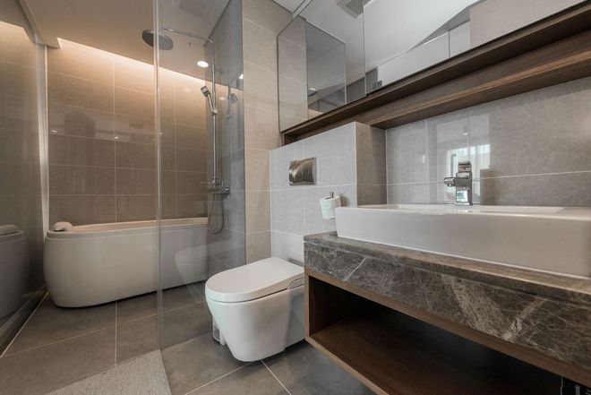 Modern bathroom with bathtub, toilet, and dark stone vanity with large mirror