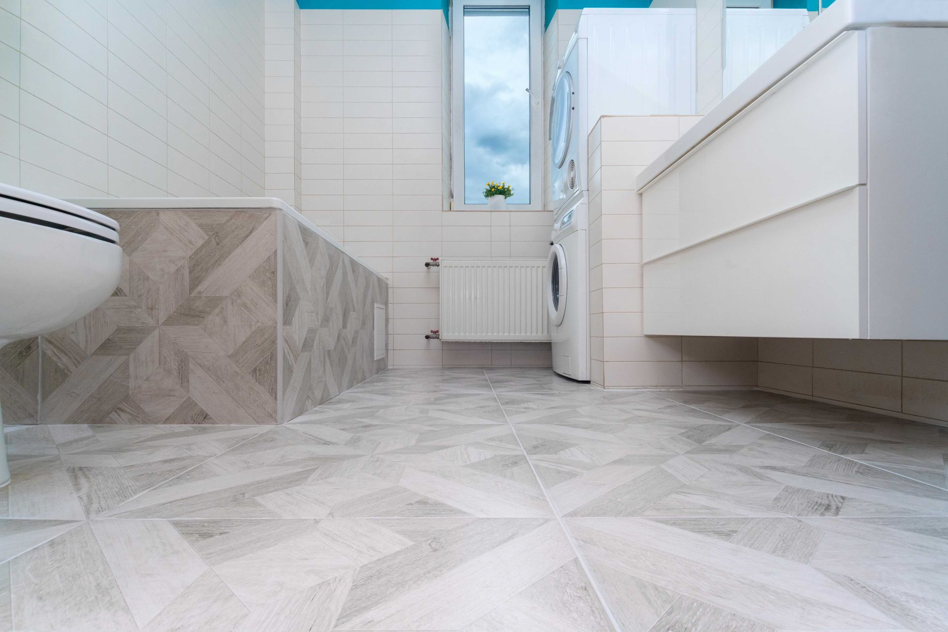 Modern bathroom with white tiled floor, vanity, bathtub, and window near the toilet Modern bathroom with white tiled floor, vanity, bathtub, and window near the toilet