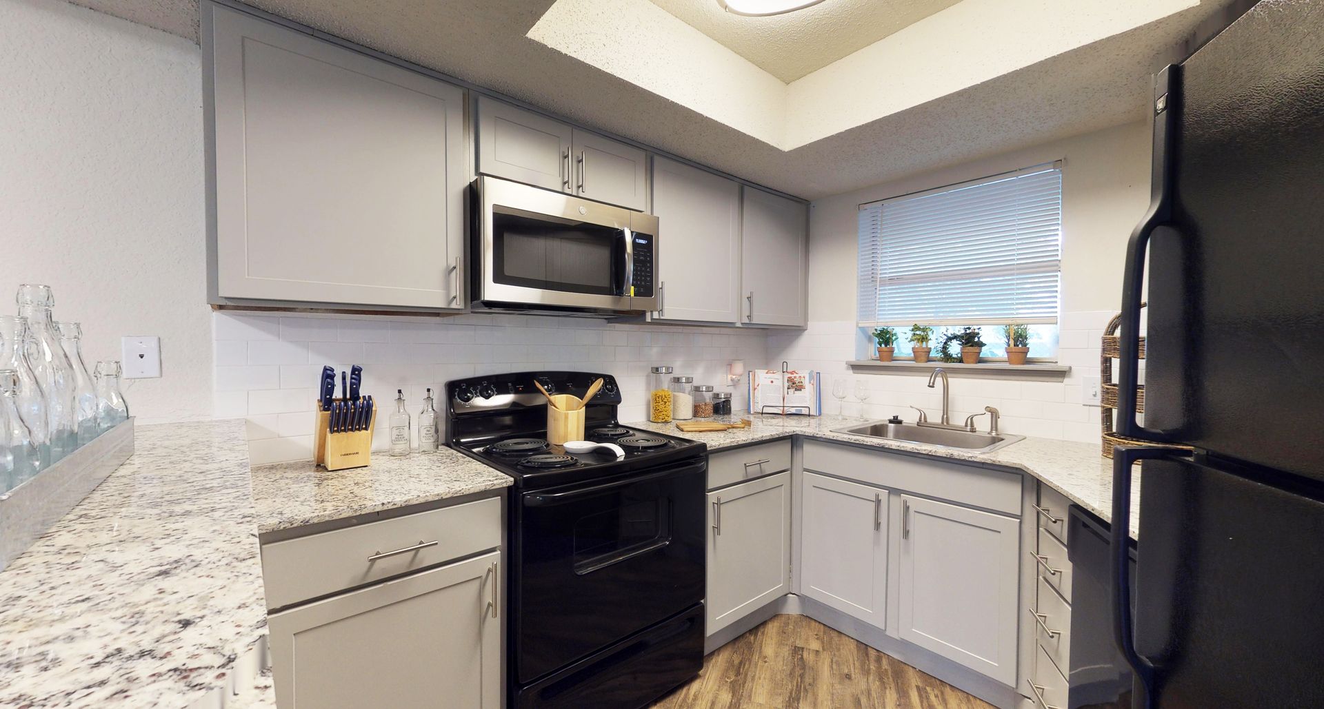 Modern kitchen with white cabinets, black appliances, granite countertops, and a window nook.