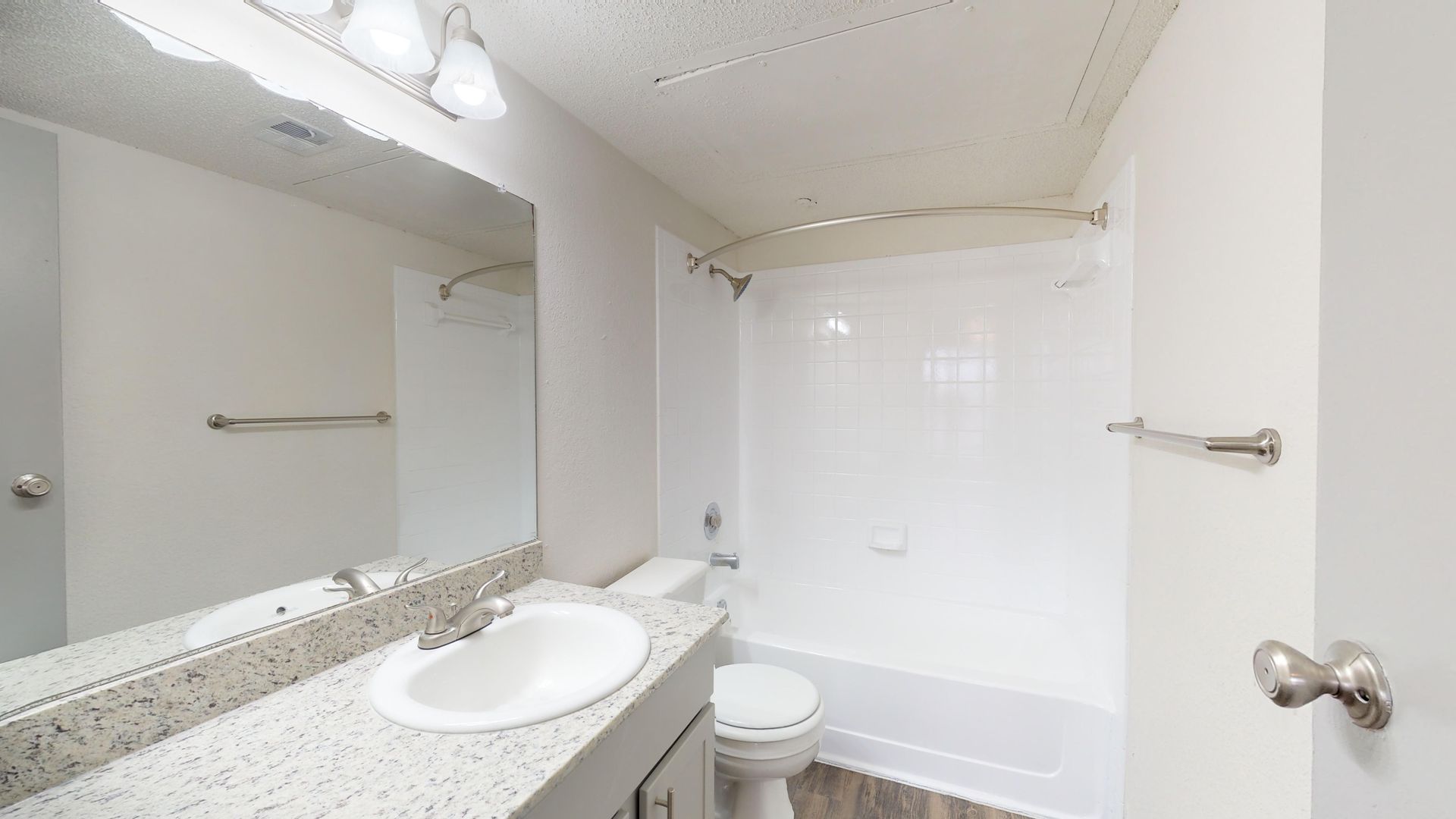 Bright white bathroom with vanity, sink, mirror, toilet, and bathtub/shower combination.