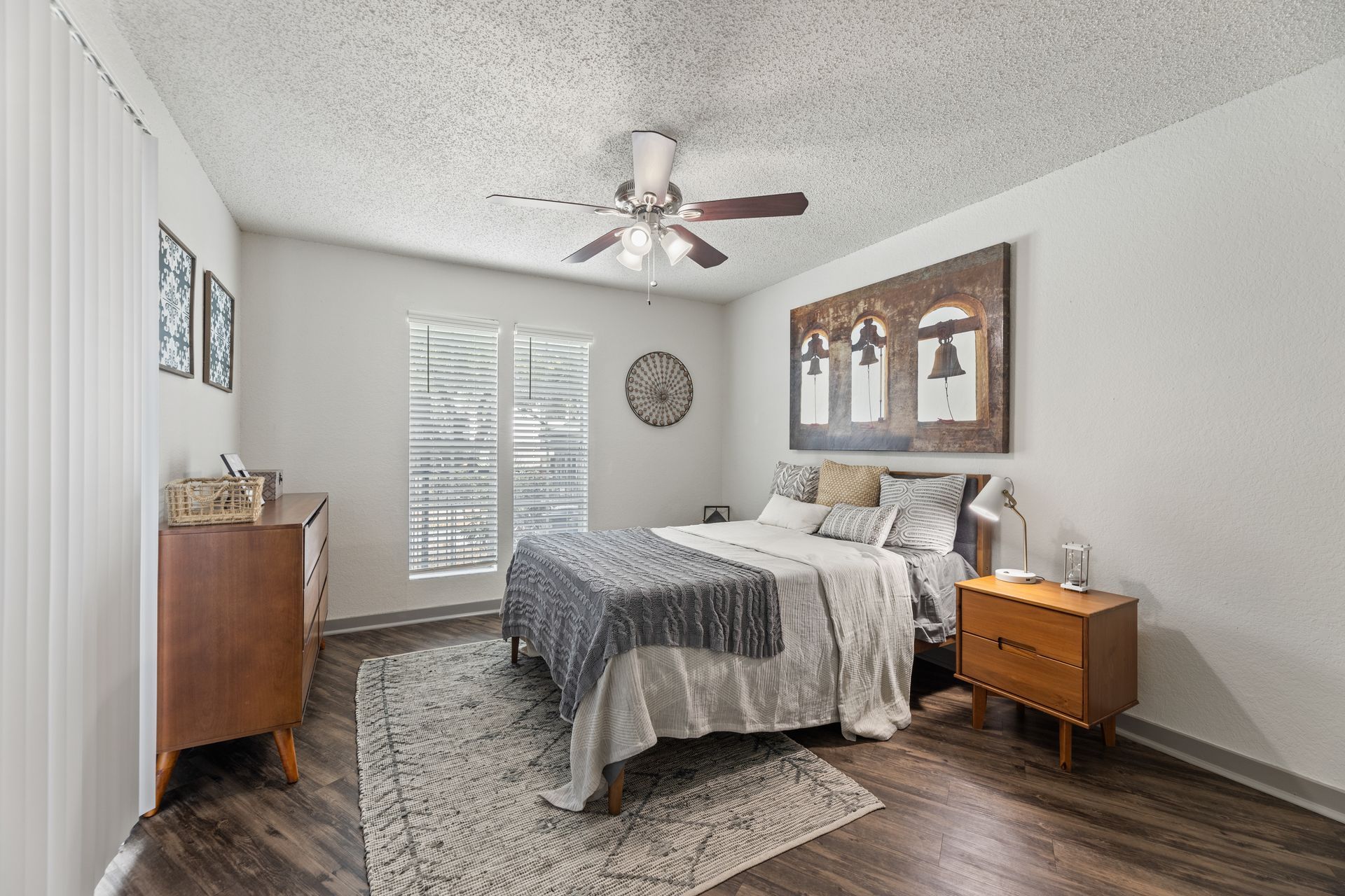 Modern bedroom with a bed, nightstands, dresser, ceiling fan, and large framed wall art