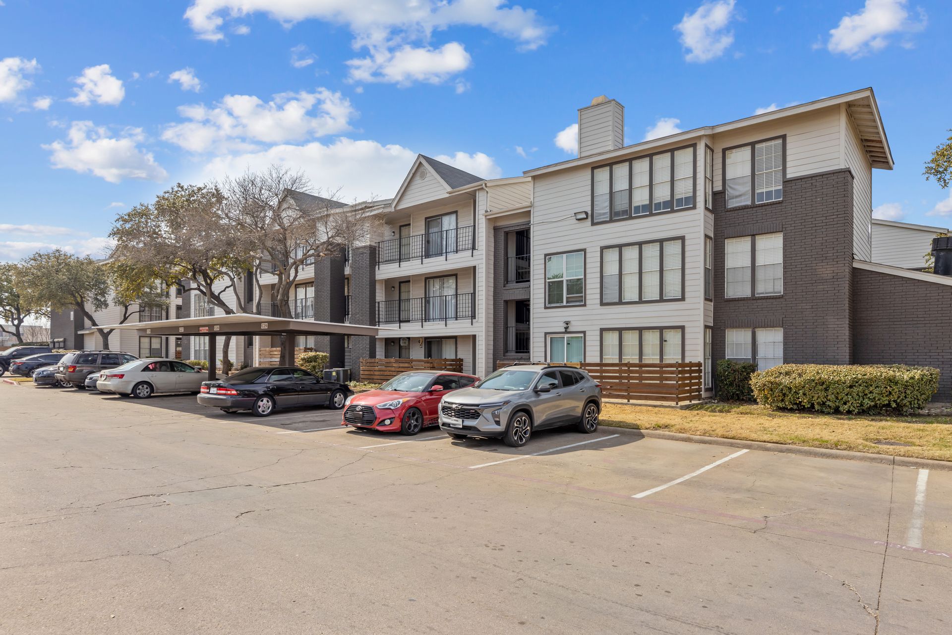 Apartment complex with parked cars under a bright blue sky
