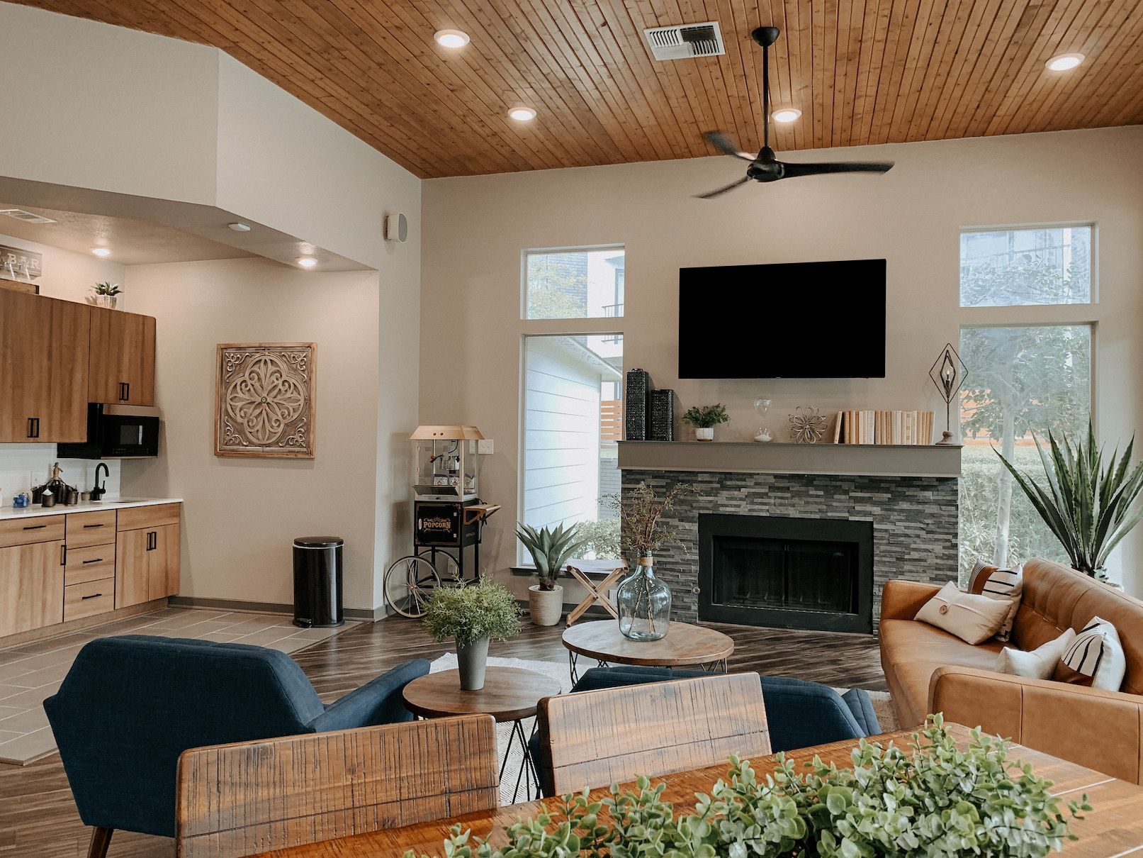 Modern living room with vaulted wood ceiling, fireplace, large TV, and patterned rug