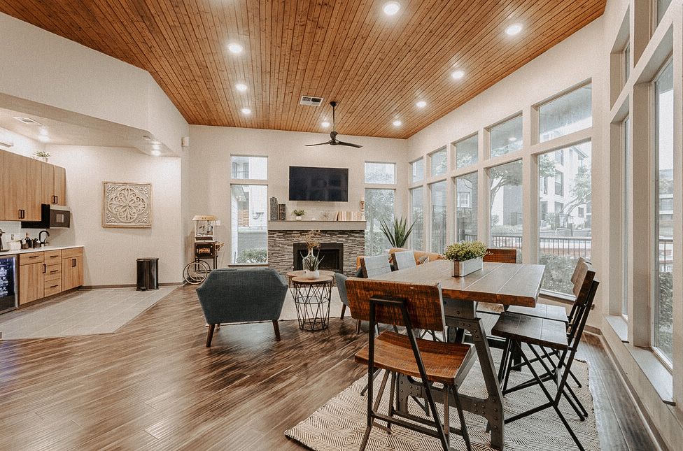 Bright modern living-dining room with wood ceiling, large windows, and a dining table by the kitchen