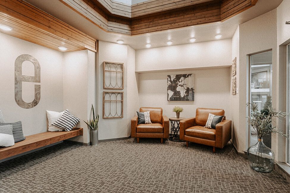 Modern lobby with tan chairs, bench seating, patterned carpet, and wall decor in a bright waiting area