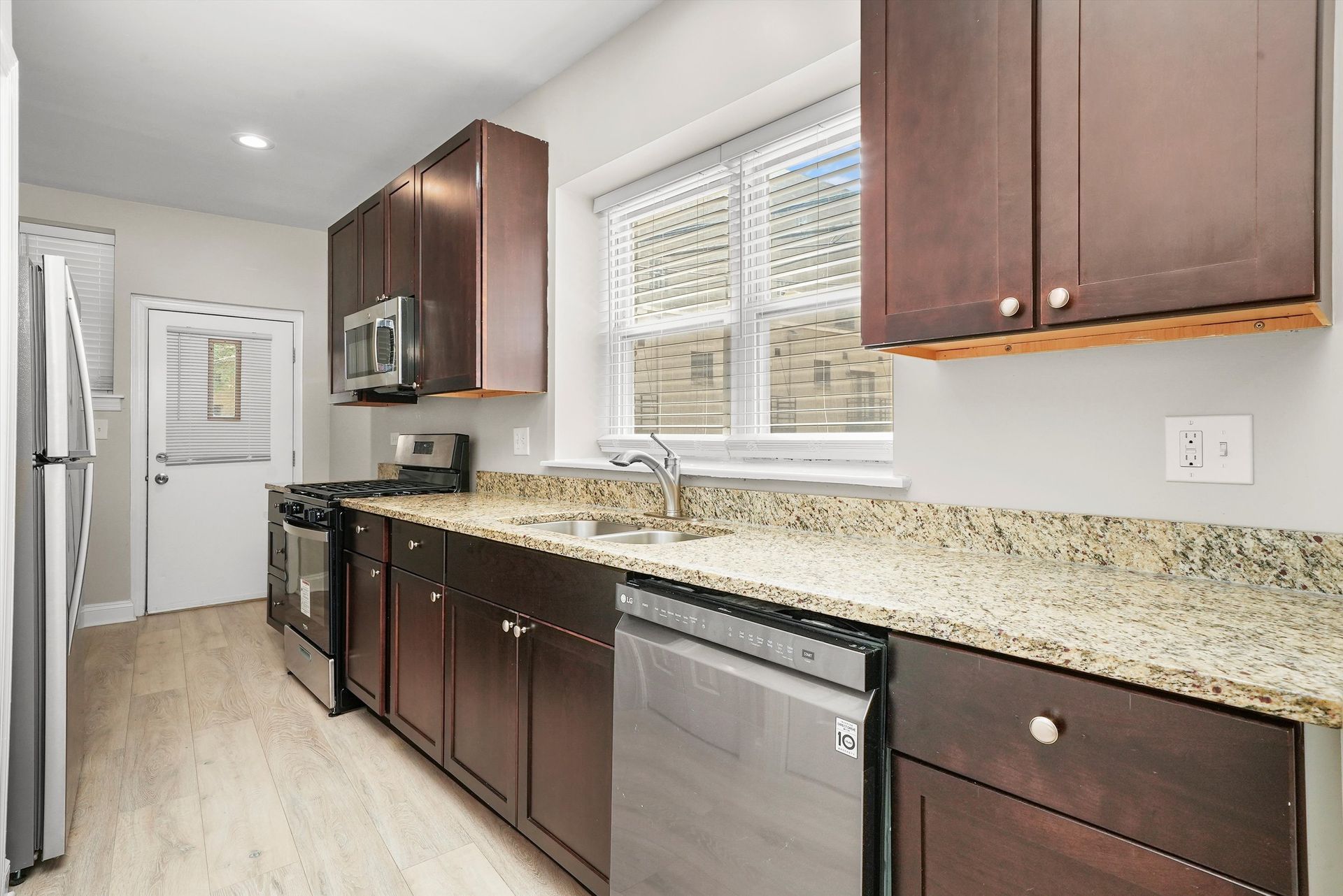 Kitchen with brown cabinets, stainless steel appliances, and light countertops.