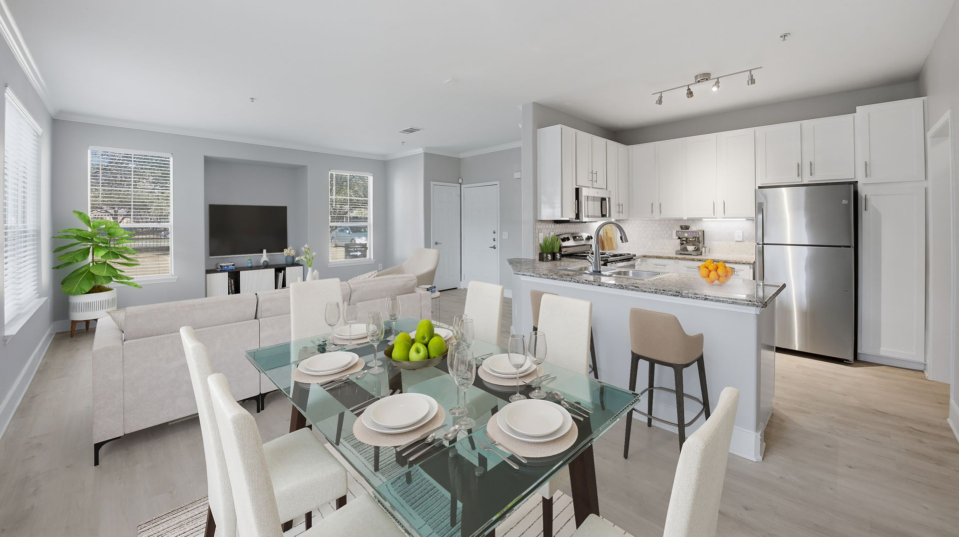 Bright modern living room with gray seating, TV, large windows, and light wood floors at Westpark Ranch Apartments in Houston, TX.