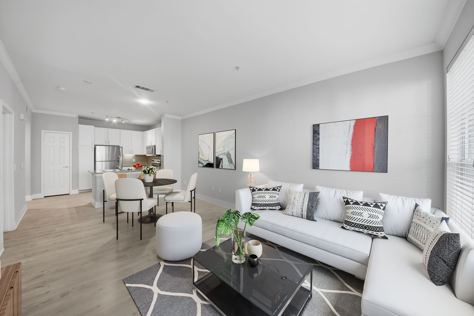 Bright open living room with white sofa, gray rug, dining area, and kitchen in the background at Westpark Ranch Apartments in Houston, TX.