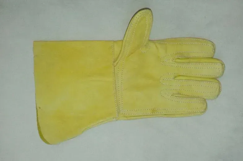Un guante de soldar de cuero amarillo sobre un fondo liso.
