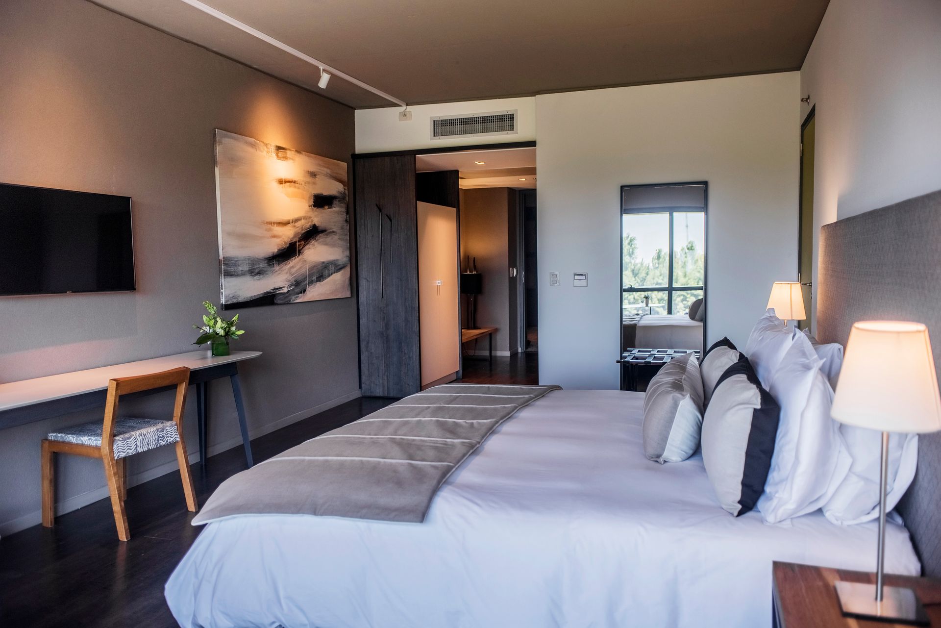 Una habitación de hotel con una cama grande, escritorio, silla y televisión.