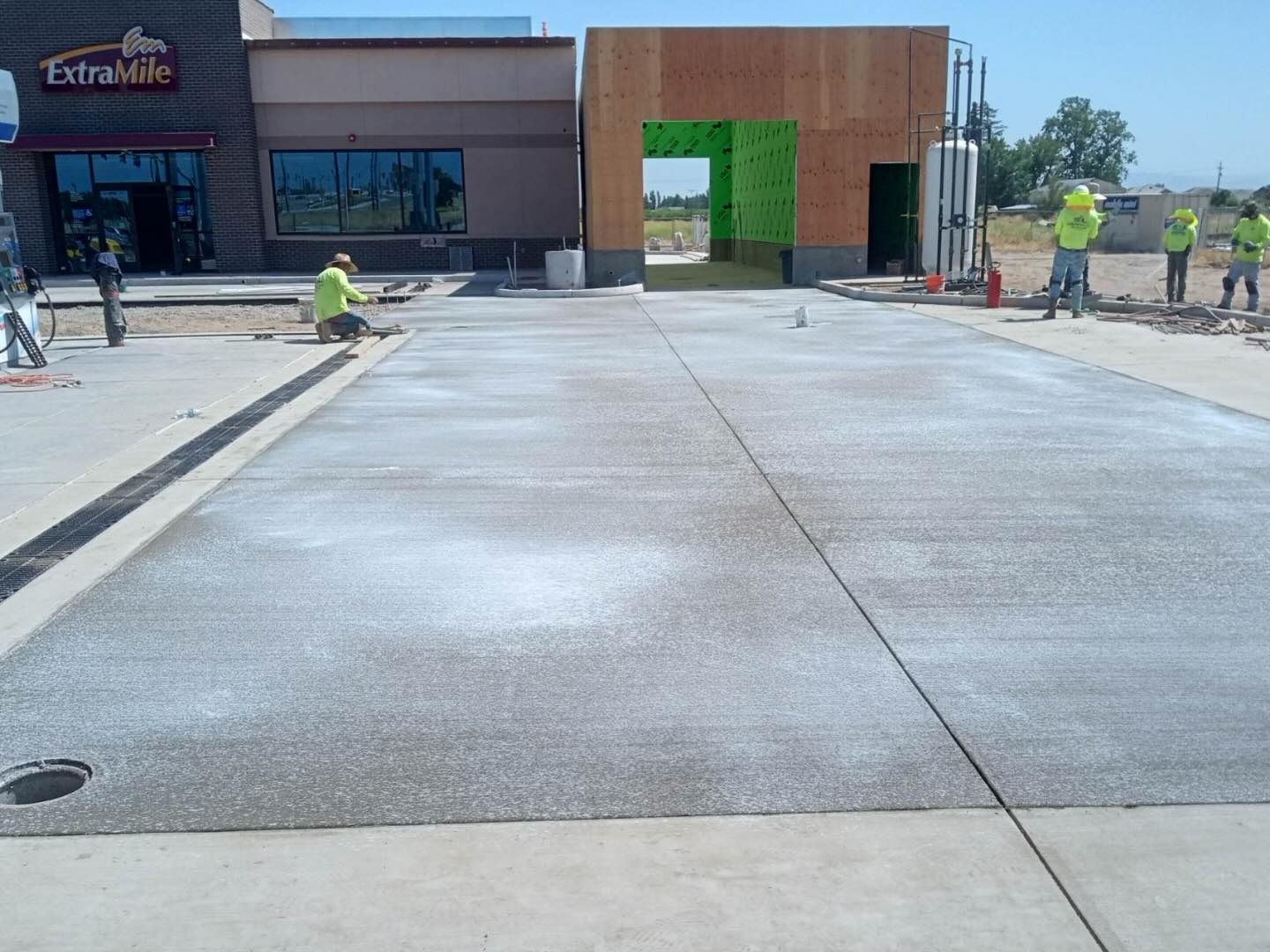 Outdoor storefront with workers finishing a concrete walkway in front of a building entrance