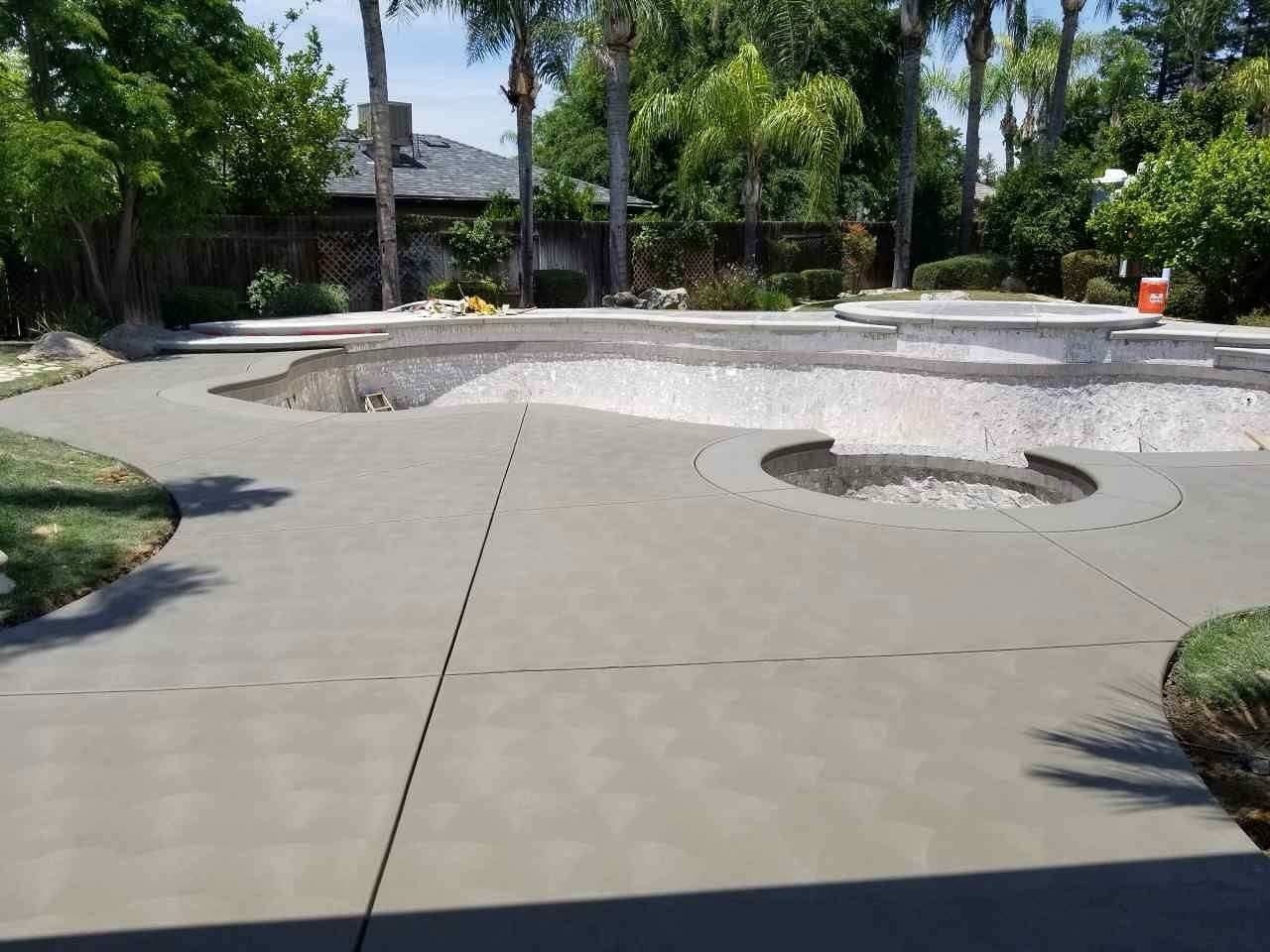 Empty public pool with curved concrete deck and trees in the background